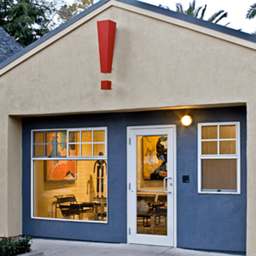 View of the front entrance to the Marketing by Design offices, featuring a large red exclamation mark hanging above the door.