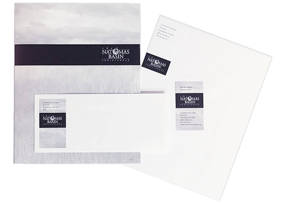 Different pieces in the TNBC stationery set, including a folder, business card, envelope, and letterhead.