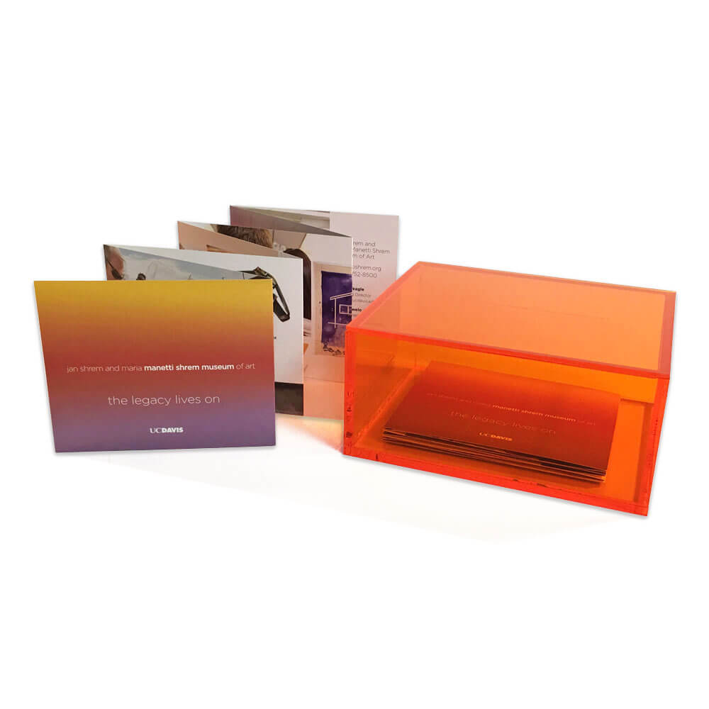Accordion-fold brochure propped up next to a bright orange display box.